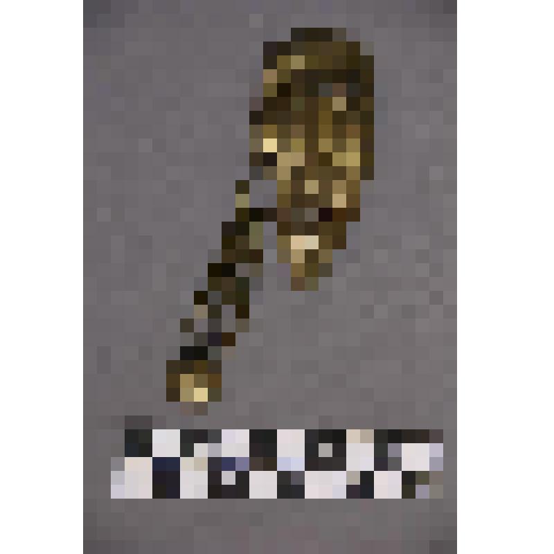 коллекция В.Ф. Лагодича. Талисман на металлической пластине в виде лица человека. С прорезанными глазами ноздрями и ртом. Украшен серьгой с 3 подвесками, к центральной крепится еще одна. С обратной стороны наклеена ткань зеленого цвета